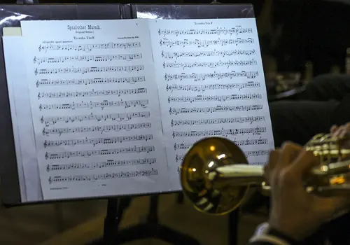Nahaufnahme der Noten auf einem Notenständer. Rechts im Bild ist eine Trompete.