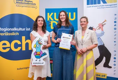 Teilnehmende Person und Vortragende posieren mit Zertifikat.