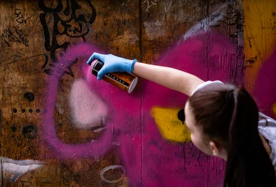 ein Mädchen sprayt etwas auf eine Graffitiwand