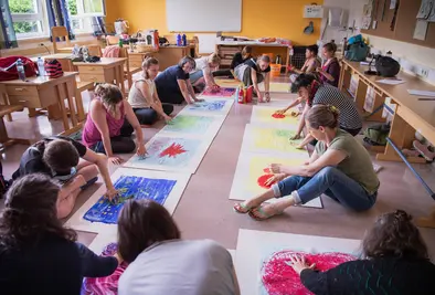 Teilnehmende sitzen am Boden und malen mit ihren Händen Bilder.