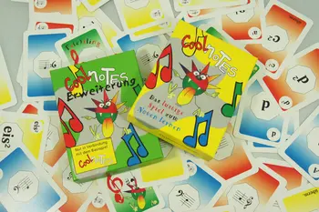 Das gelbe Basisspiel „Cool Notes“ und die grüne Erweiterung liegen auf einer Fläche voller einzelner Spielkarten.