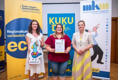 Teilnehmende Person und Vortragende posieren mit Zertifikat.