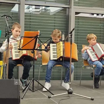 Kinder spielen auf ihrem Akkordeon.
