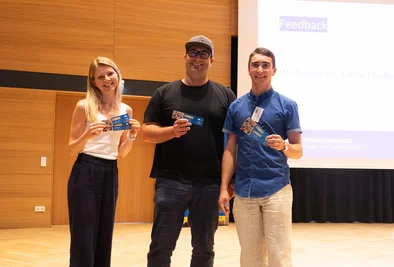Drei Gewinnerinnen und Gewinner stehen auf der Bühne.