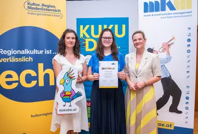 Teilnehmende Person und Vortragende posieren mit Zertifikat.