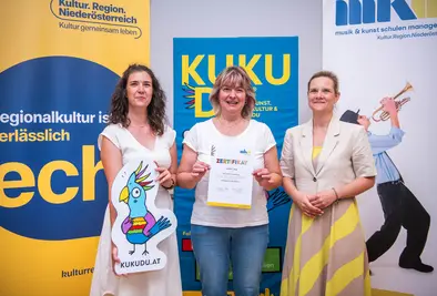 Teilnehmende Person und Vortragende posieren mit Zertifikat.