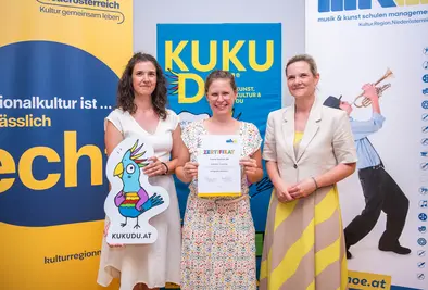 Teilnehmende Person und Vortragende posieren mit Zertifikat.