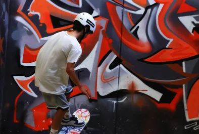 ein Skateboarder turnt vor einer Graffitiwand