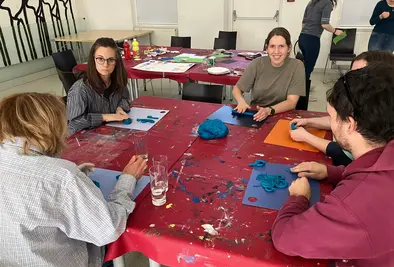 Fünf Personen sitzen an einem Tisch und basteln individuell etwas mit Knetmasse.