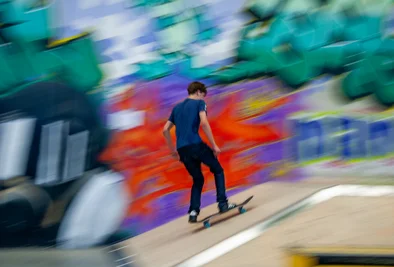 ein Skateboarder turnt vor einer Graffitiwand