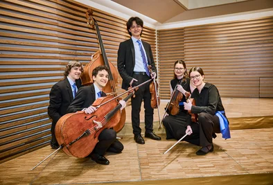 5 Musikerinnen und Musiker posieren mit ihren Instrumenten für ein Foto