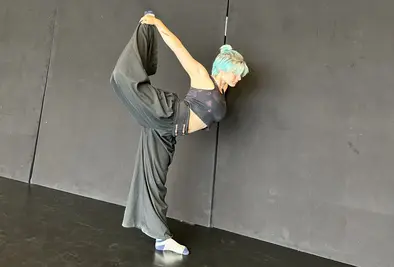 Eine Person dehnt sich im Stehen im Spagat.