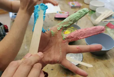 Mehrere Personen schmieren sich Farbe auf die Finger.