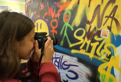 ein Mädchen fotografiert eine Graffitiwand