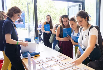 Mehrere Personen informieren sich an einem Ausstellungstisch mit Unterlagen und Informationsmaterial.