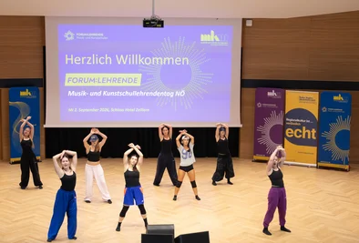 Tanzgruppe mit erhobenen Armen bei einer Bühnenperformance.