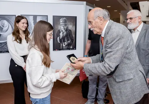 Ein Mädchen bekommt ihre Auszeichnung von einem älteren Herren überreicht.
