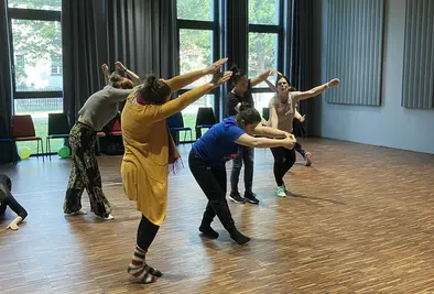 Personen strecken ihre Arme von sich während sie durch den Raum wandern.