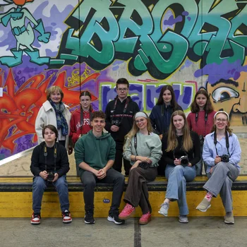 10 Personen sitzen vor einer Graffitiwand