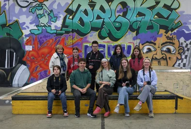 10 Personen sitzen vor einer Graffitiwand