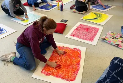 Nahaufnahme einer Teilnehmerin, die ihre Hände auf ihr gemaltes Bild presst.