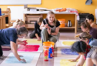 Teilnehmende sitzen am Boden und malen mit ihren Händen Bilder.
