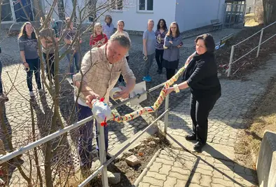 Zwei Personen befestigen die gebastelte Schlange an einem Geländer.an