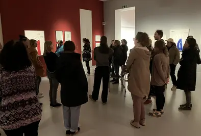 Mehrere Personen schauen sich ausgestellte Gemälde an.