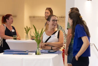 Drei Frauen unterhalten sich an einem Tisch mit Informationsmaterial.