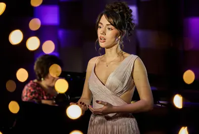 Eine junge Dame singt umgeben von verschwommenen Lichtern.