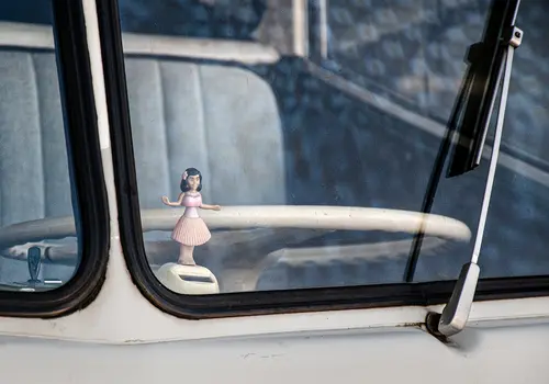 Wackelfigur auf der Armatur eines Oldtimers von außen fotografiert.