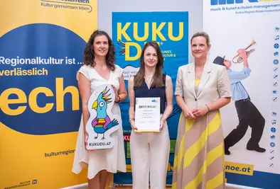 Teilnehmende Person und Vortragende posieren mit Zertifikat.