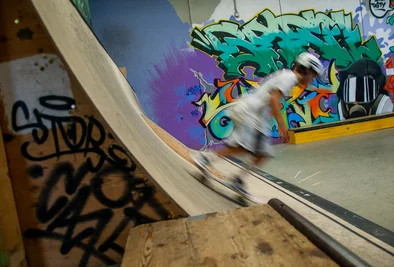 ein Skateboarder turnt vor einer Graffitiwand