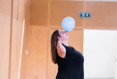 Eine Person balanciert einen Luftballon auf ihrer Nase.