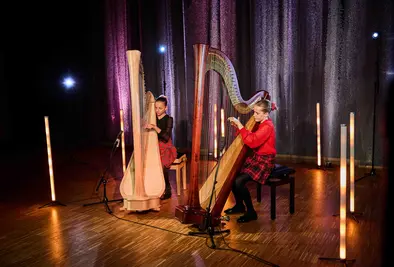 Zwei Mädchen spielen jeweils auf einer Harfe, vor ihnen stehen Mikrofone.