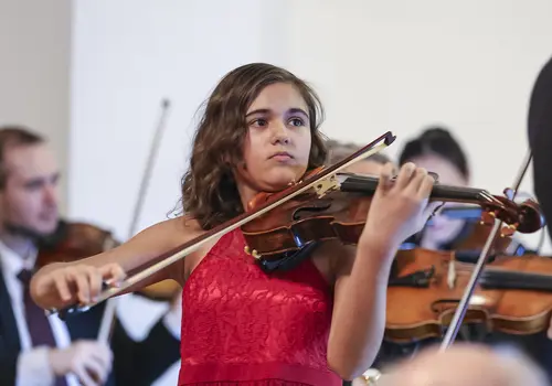 Ein Mädchen spielt fokussiert auf der Geige.