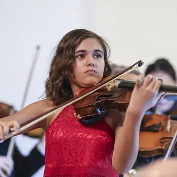 Ein Mädchen spielt fokussiert auf der Geige.