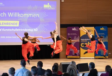 Tanzgruppe in roten und schwarzen Kostümen während einer Bühnenperformance.