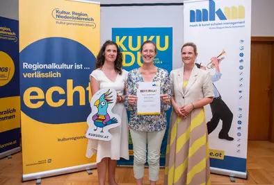 Teilnehmende Person und Vortragende posieren mit Zertifikat.