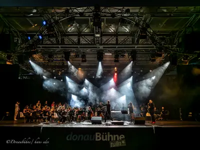 Orchester sitzt im Licht auf einer Bühne