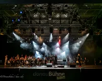 Orchester sitzt im Licht auf einer Bühne