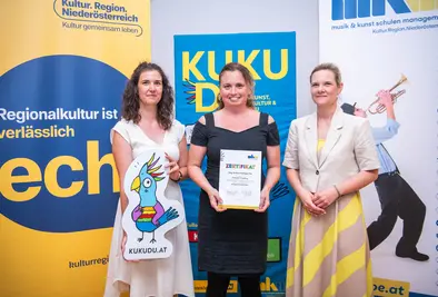 Teilnehmende Person und Vortragende posieren mit Zertifikat.