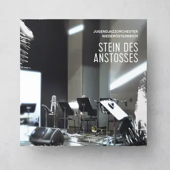 CD-Hülle mit einem Foto eines leeren Proberaums mit Instrumenten und Notenständern. Oben rechts steht der Text: „Jugendjazzorchester Niederösterreich – Stein des Anstoßes“.