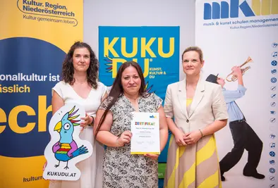 Teilnehmende Person und Vortragende posieren mit Zertifikat.