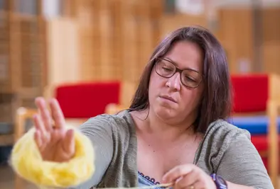 Eine Person wickelt Wolle um ihren Arm auf.