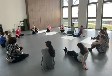 Personen sitzen in einem Kreis auf dem Boden.