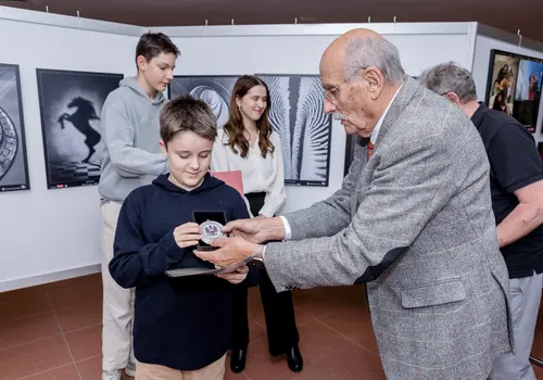 Ein Junge bekommt seine Auszeichnung von einem älteren Herren überreicht.