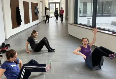 Drei Frauen sitzen nur mit dem Gesäß auf dem Boden am Gang