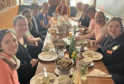 Gruppenfoto der Teilnehmenden, die an einem gedeckten Tisch sitzen.