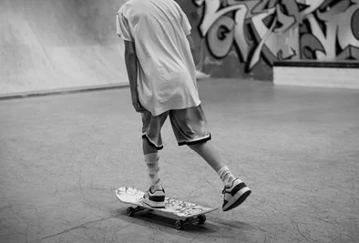ein Skateboarder turnt vor einer Graffitiwand